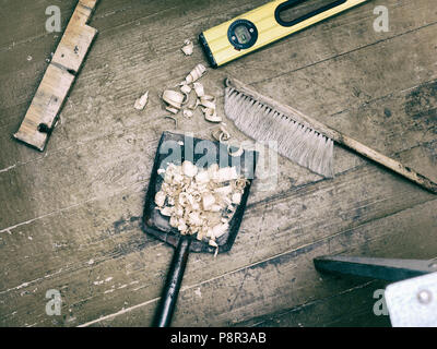 Overhead filterd shot of a metal dustpan with wood chip on the wooden floor Stock Photo