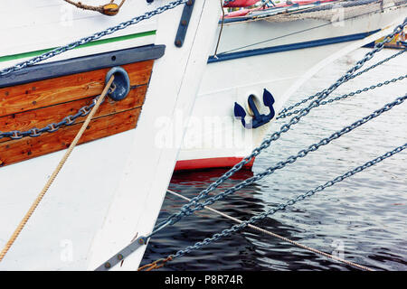 Ropes and iron chains on the nose of wooden ships with an anchor on the waves of the Bay in the port. Elements of a sailboat. Stock Photo