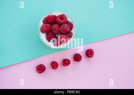 Flat lay of fresh tasty granola with rasberry on pink and turquoise background. Stock Photo