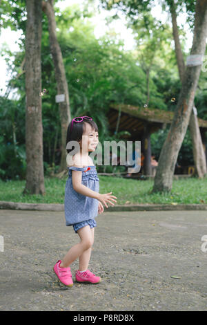 Beautiful little haired hair girl, has happy fun smiling face, pretty eyes, short hair, playing soap bubbles, dressed, Child portrait. Creative concep Stock Photo