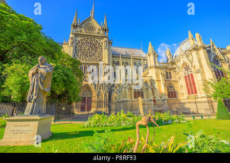 Pope John Paul II statue on side of church Notre Dame of Paris, France. Gothic architecture of Cathedral of Paris, Ile de la cite. Beautiful sunny day in the blue sky. Stock Photo