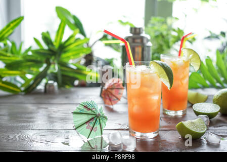 Zombie Cocktail with Rum, garnished with lime. Cold sweet summer fruit red alcohol cocktail, refreshing drink on wooden table, copy space. Stock Photo