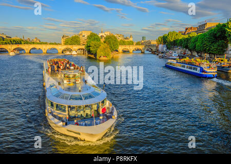 Paris, France - July 1, 2017: Tourist cruise on Seine river. Bateau mouche from Pont Neuf bridge and Notre Dame church on background. Aerial view of touristic cruise fro Pont des Arts at sunset.