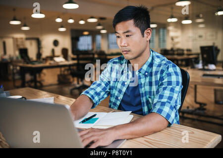 Young Asian designer working late at his office desk Stock Photo