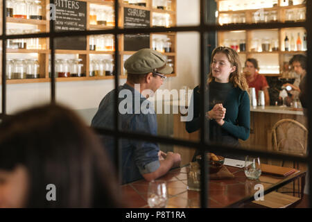 Smiling young waitress talking with a bistro customer Stock Photo