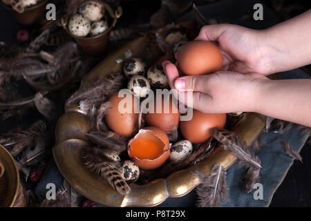 children's hands in the frame, Easter eggs large and small, feathers. Photo in vintage style. Rural accessories. Copy space Stock Photo