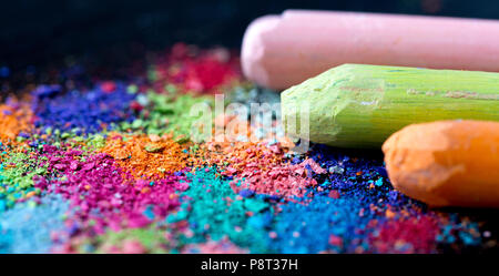 Crumbs of multi-colored chalk on a black background. Joy, Carnival, Panorama. A game for children. Art Stock Photo