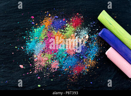 Crumbs of multi-colored chalk on a black background. A game for children. Art Stock Photo