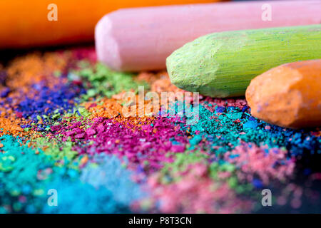Crumbs of multi-colored chalk on a black background. A game for children. Art Stock Photo
