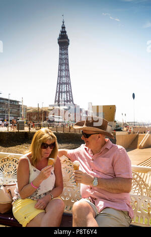 UK, England, Lancashire, Blackpool, North Pier, visitors sat on bench in sunshine eating icecreams Stock Photo