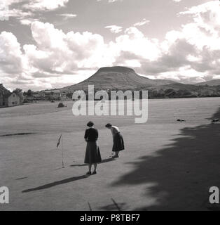 1950s, two lady golfers on a putting green on a golf course, ireland. Stock Photo