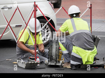 Telephone engineers working on fibre optic cables on busy road in Spain Stock Photo
