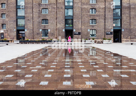 Low shooting angle of the University of the Arts London (UAL) in Granary Square, King's Cross, showing a woman in a pink coat positioned centrally Stock Photo