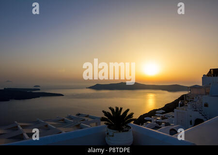 Incredibly romantic scene on Santorini. Fira, Greece. Amazing sunset view towards the deep Aegean sea crystal waters with white house roofs with singl Stock Photo