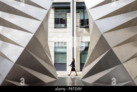 Woman walking between Paternoster Vents (Angels Wings) stainless steel sculpture by Thomas Heatherwick on Ave Maria Lane, Ludgate Hill, London Stock Photo