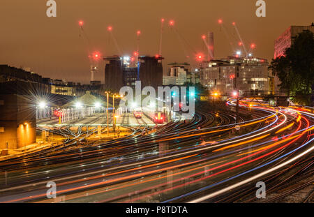 Night time view from Ebury Bridge towards the deconstructed Battersea Power Station, London, with light trails of trains to and from Victoria station Stock Photo