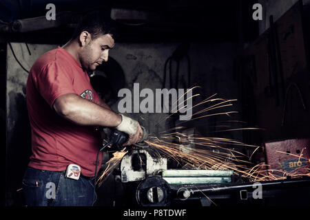 Turkish worker using an angle grinder on metal in an indoor workplace. Stock Photo