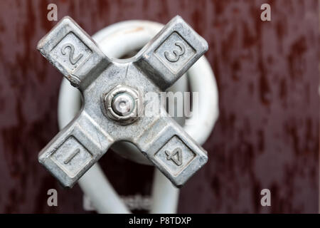 Close up view of industrial metal valve with numbers on it on maroon grunge background Stock Photo