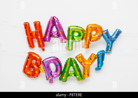 HAPPY BIRTHDAY balloon letters hanging on a white wall Stock