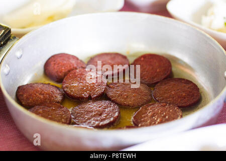 Turkish breakfast. Fried sausage in a small frying pan on ttable Stock Photo