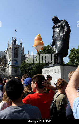 London, UK. 13th July, 2018. A Donald Trump baby blimp, mocking the American President, is flying bhind the Winston Churchill statue above Westminster Square in London, as the President of the United States of America visits London, and has meetings with Prime Minister Theresa May and HM Queen Elizabeth II. Donald Trump baby blimp protest, London, on July 13, 2018. Credit: Paul Marriott/Alamy Live News Stock Photo