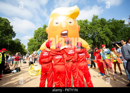London/United Kingdom - July 13, 2018: Donald Trump’s visit to England is met with protests and a blimp flying over London’s Parliament Square. The protest team poses for the cameras with Angry Trump Baby in the background. Stock Photo