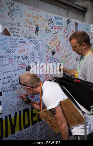 People writing on the Awaaz wall with comments for Donald Trump.  Tens of thousands of people marched and protested against the Trump visit to the UK. The march started in Regent Street and ended in Trafalgar Square. Stock Photo