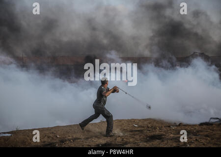 Jabaliya, Gaza strip, Gaza. 13th July, 2018. Palestinian protester seen throwing back stones at the Israeli forces.Protest at the Gaza Strip border by Palestinian citizens that resulted to clashes between the Israeli forces in which a 15-year-old Palestinian was killed. Credit: Nidal Alwaheidi/SOPA Images/ZUMA Wire/Alamy Live News Stock Photo