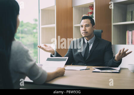 Business negotiation, male partners arguing, funny easygoing woman keeping calm in stressing situation, meditating with composed smile, dealing with e Stock Photo