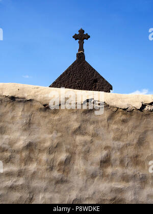 Cross on a gravestone behind a wall in a cemetery in Auvergne, France Stock Photo