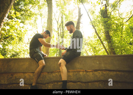 Fit man assisting his teammate to climb a wooden wall Stock Photo