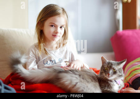 Little preschooler girl in pajamas and her cat on sunny morning Stock Photo