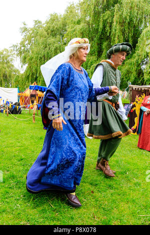 Medieval dancing outdoors. Living history couple dressed in traditional costume dancing on the grass, holding hands Stock Photo