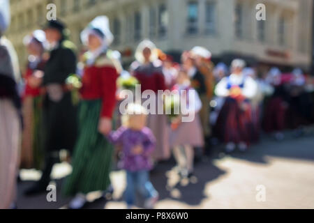 The people in the convoy with the children in national costumes on the street in celebration. Blurry Stock Photo