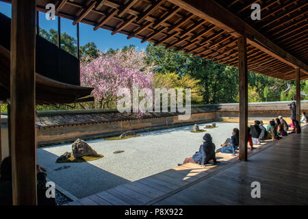 Japanese tourists enjoy tranquility at Ryoanji Temple in Kyoto, Japan. This Zen Buddhist temple is famous for its rock garden. Stock Photo