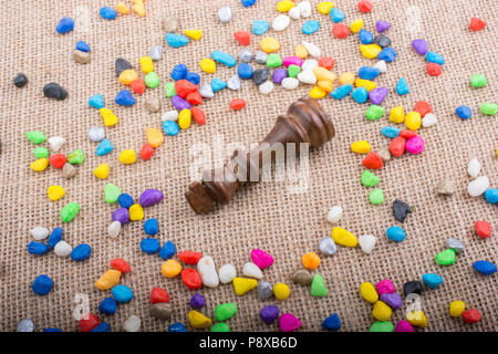 Chess king amid colorful pebbles on canvas background Stock Photo