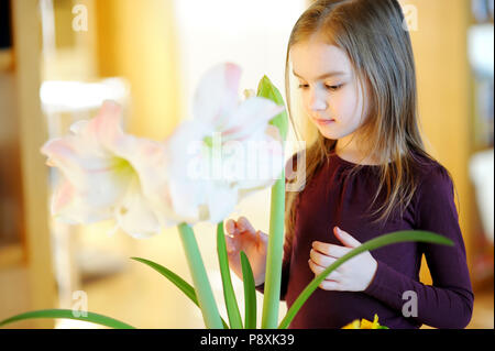 Adorable little girl taking care of plants and flowers at home Stock Photo