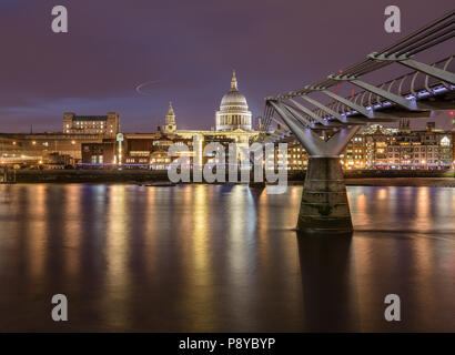 Long exposure landscape view of St Pauls Cathedral and the London Millennium Footbridge at night with lights reflected in the River Thames