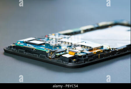 Disassembled mobile phone in the service centre with internal components of the camera and speaker. Stock Photo