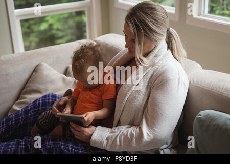 Mother and baby sitting on the sofa and using digital tablet Stock Photo