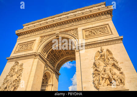 Bottom view of Arch of Triumph at center of Place Charles de Gaulle in a beautiful sunny day with blue sky. Popular landmark and famous tourist attraction in Paris capital of France in Europe.