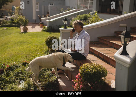 Senior man talking on mobile phone while using laptop Stock Photo