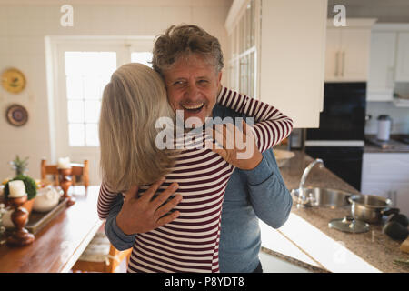 Senior couple hugging in the kitchen Stock Photo