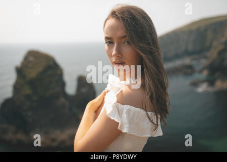 Beautiful woman standing near the sea on a breezy day Stock Photo