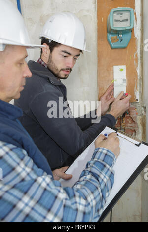 worker taking notes on his clipboard while taking to coworker Stock Photo