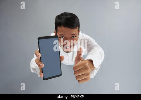Asian man hold smartphone and show thumb up isolated on gray background above top view Stock Photo