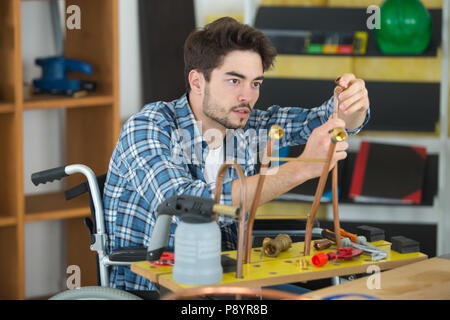 Disabled plumber working on copper pipes Stock Photo