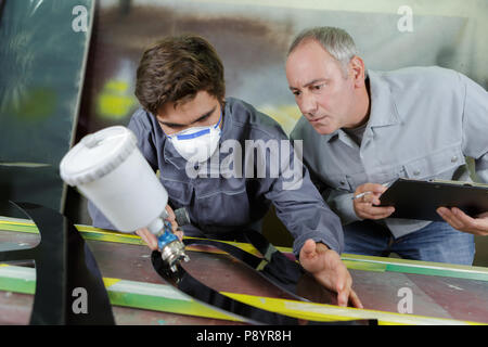 apprentice and worker painting with spray gun Stock Photo