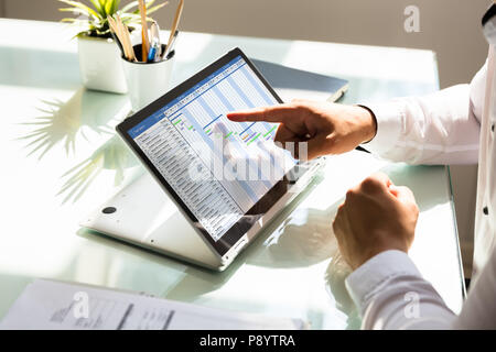 Businessman's hand analyzing gantt chart on laptop over reflective desk Stock Photo