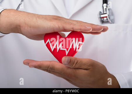 Close-up of a doctor's hand holding red heart rate Stock Photo